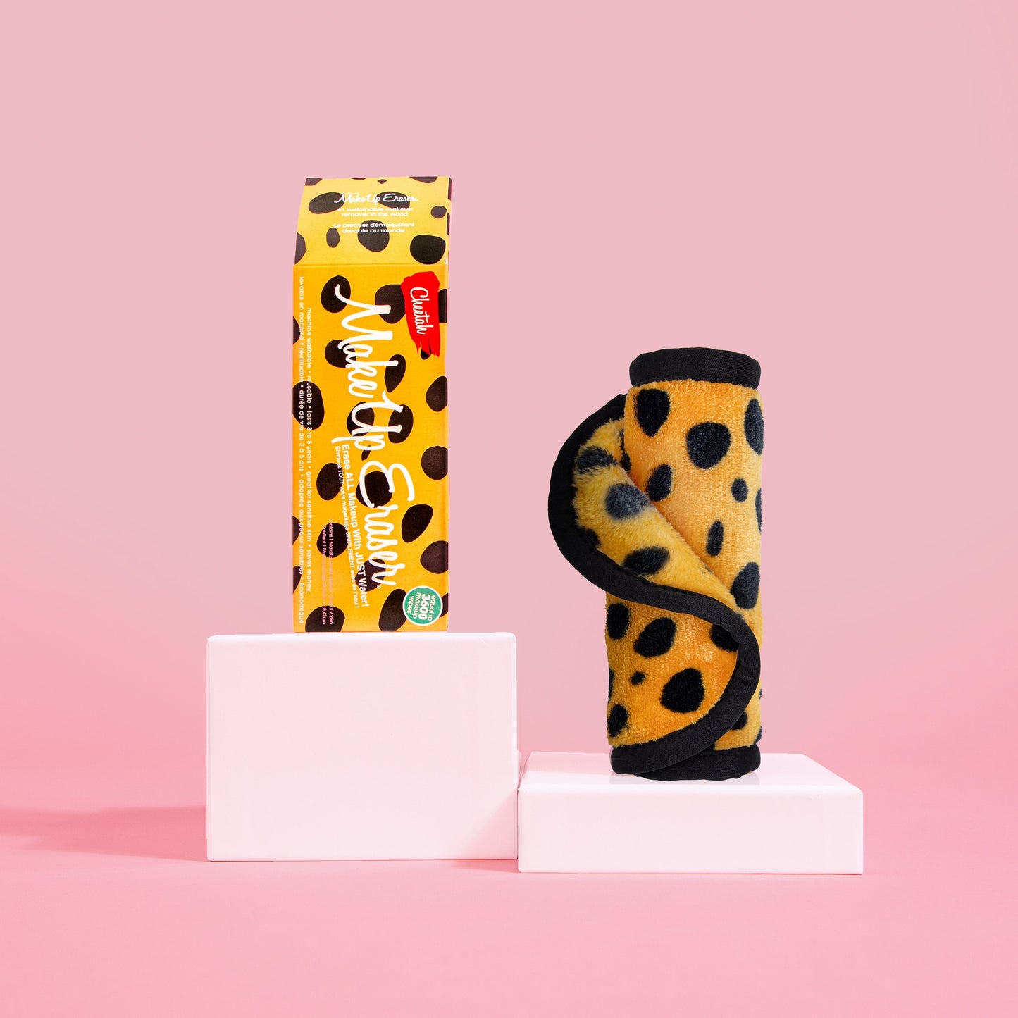 Rolled up Cheetah Print MakeUp Eraser next to packaging, both propped up on platforms.