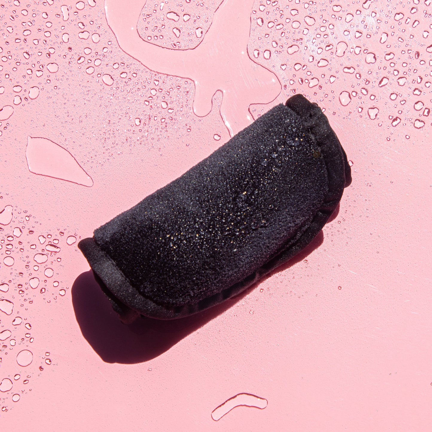 Rolled up Chic Black MakeUp Eraser surrounded by waterdrops.