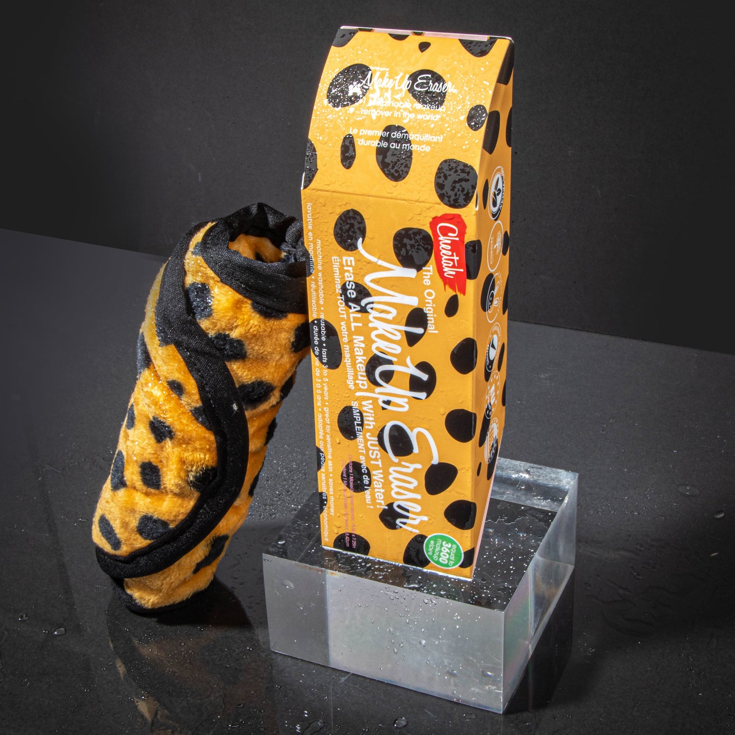 Rolled up Cheetah Print MakeUp Eraser next to packaging surrounded by waterdrops.