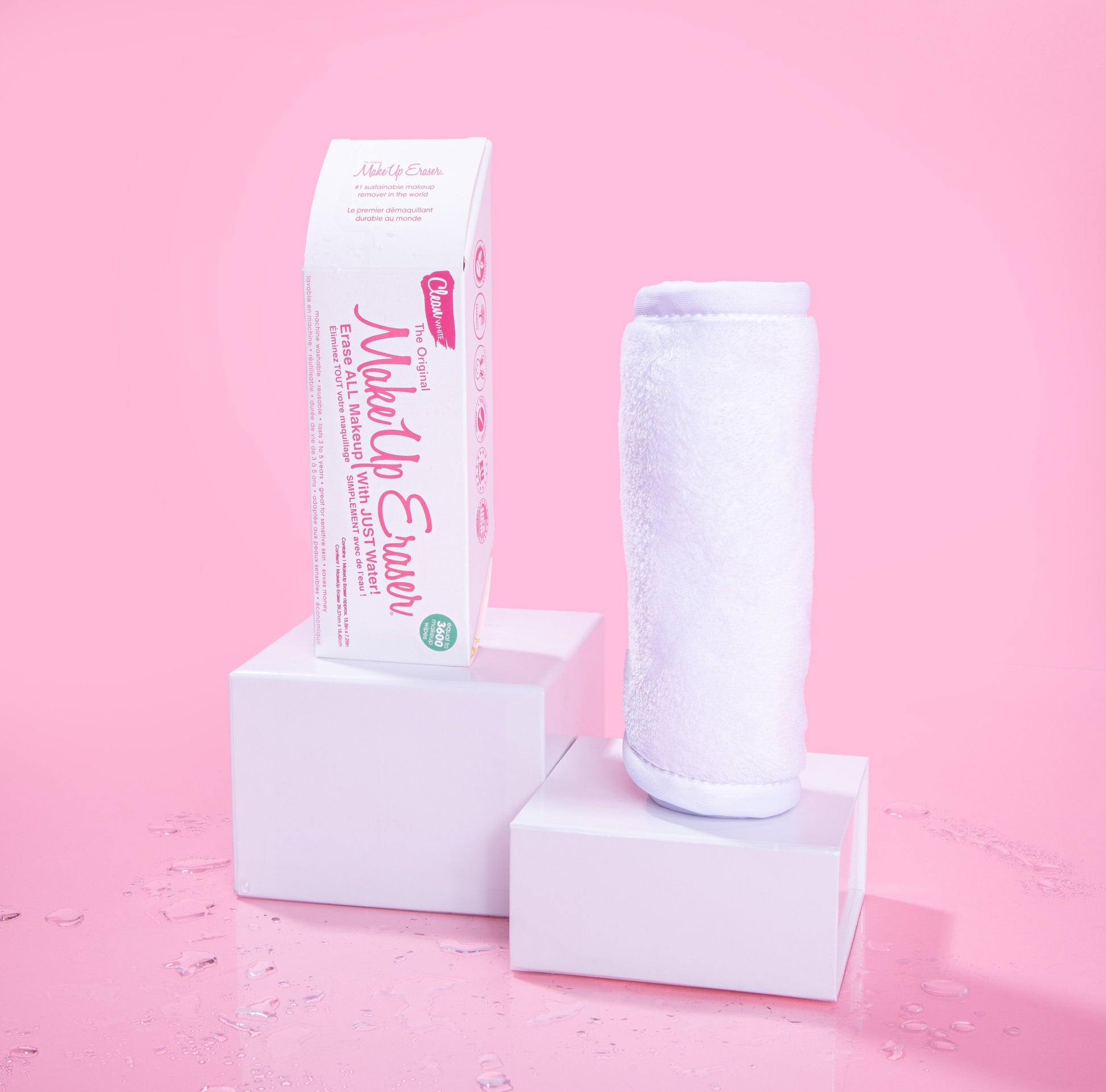 Rolled up Clean White MakeUp Eraser next to packaging, both propped up on platforms.