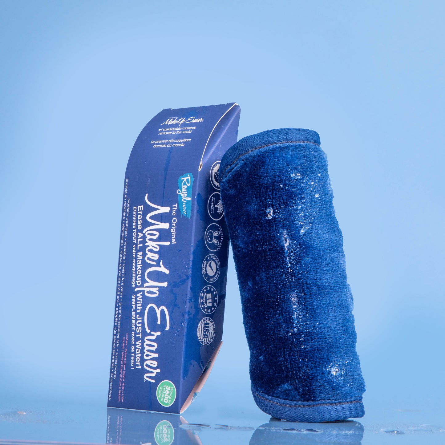 Rolled up Royal Navy MakeUp Eraser next to packaging surrounded by waterdrops.