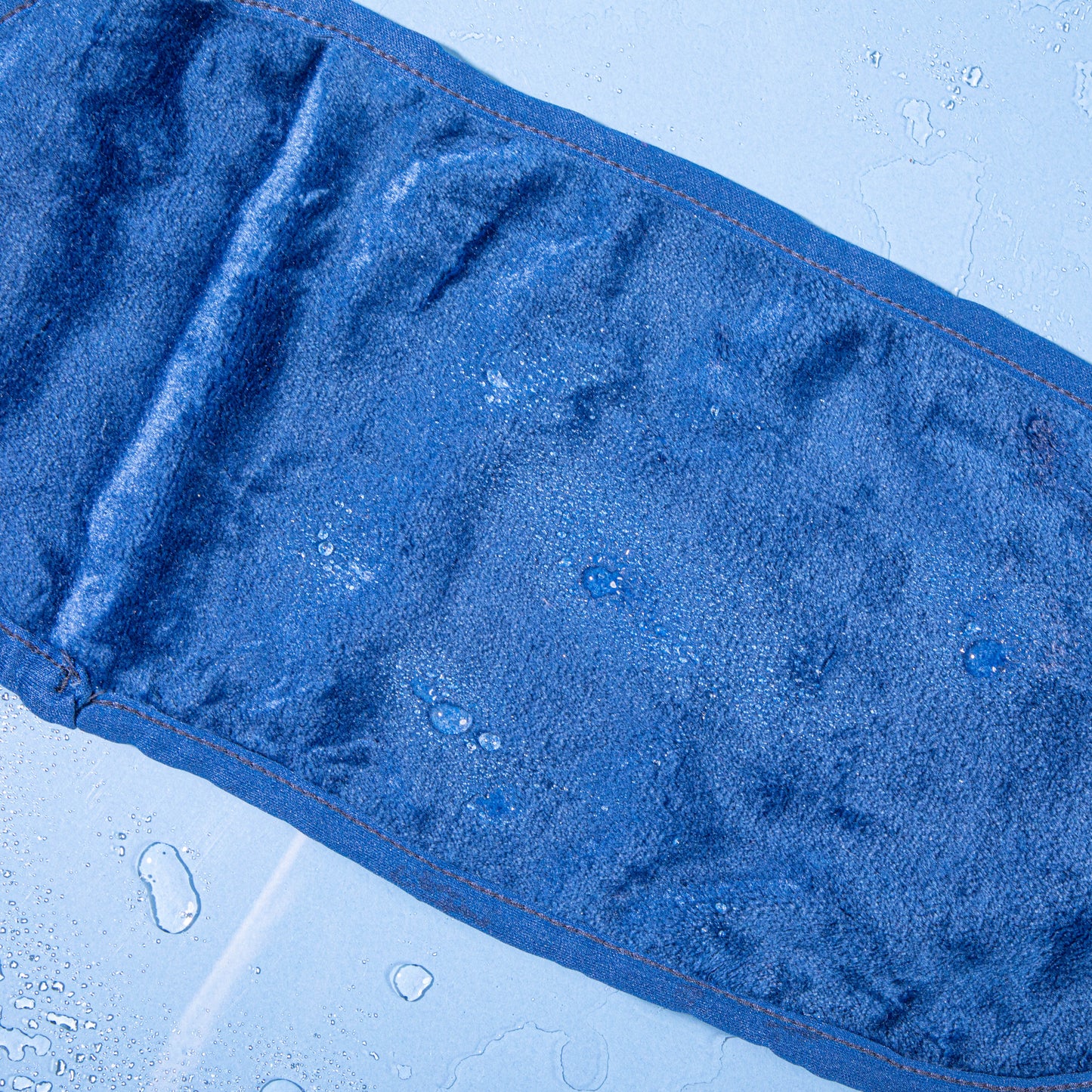 Royal Navy MakeUp Eraser laying flat surrounded by waterdrops.