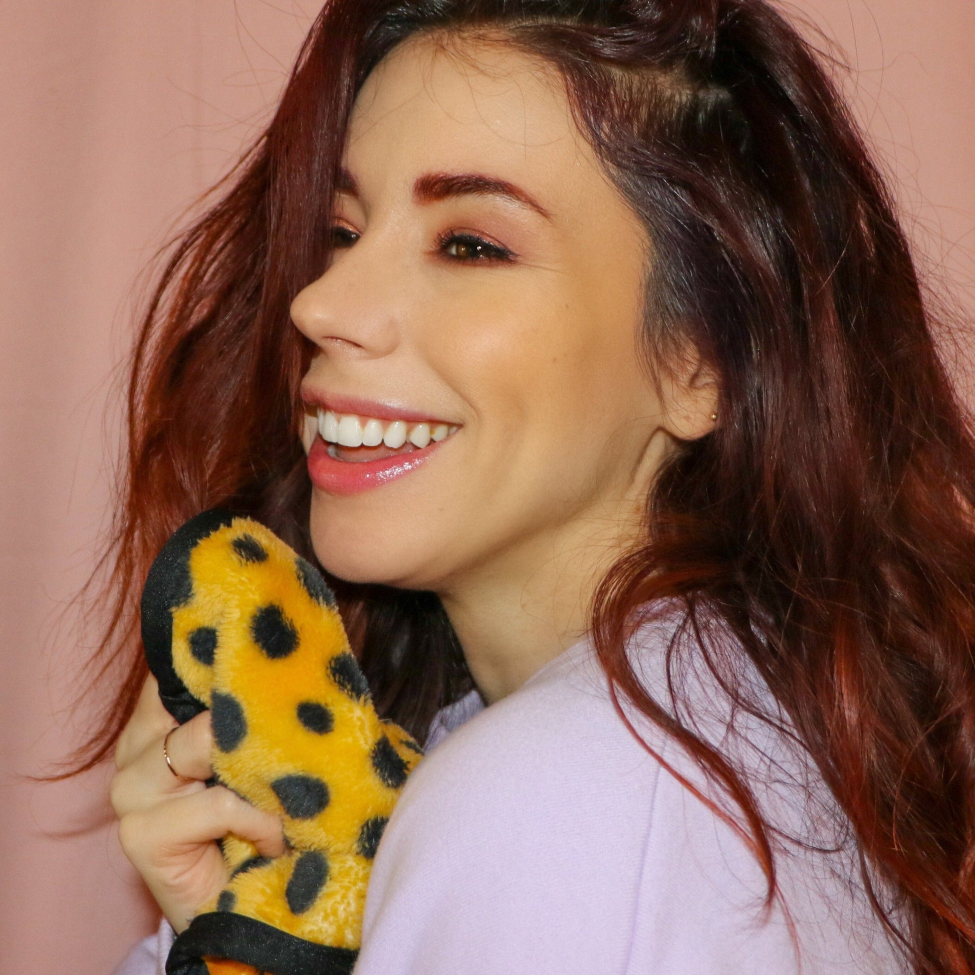 Woman smiling and holding up Cheetah Print MakeUp Eraser to her face.