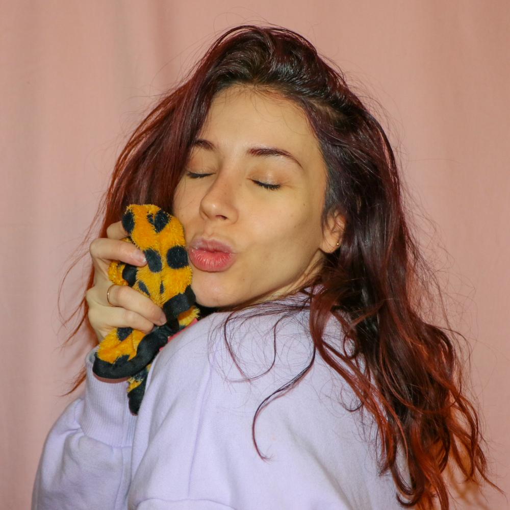 Woman holding charity: water MakeUp Eraser up to her face.