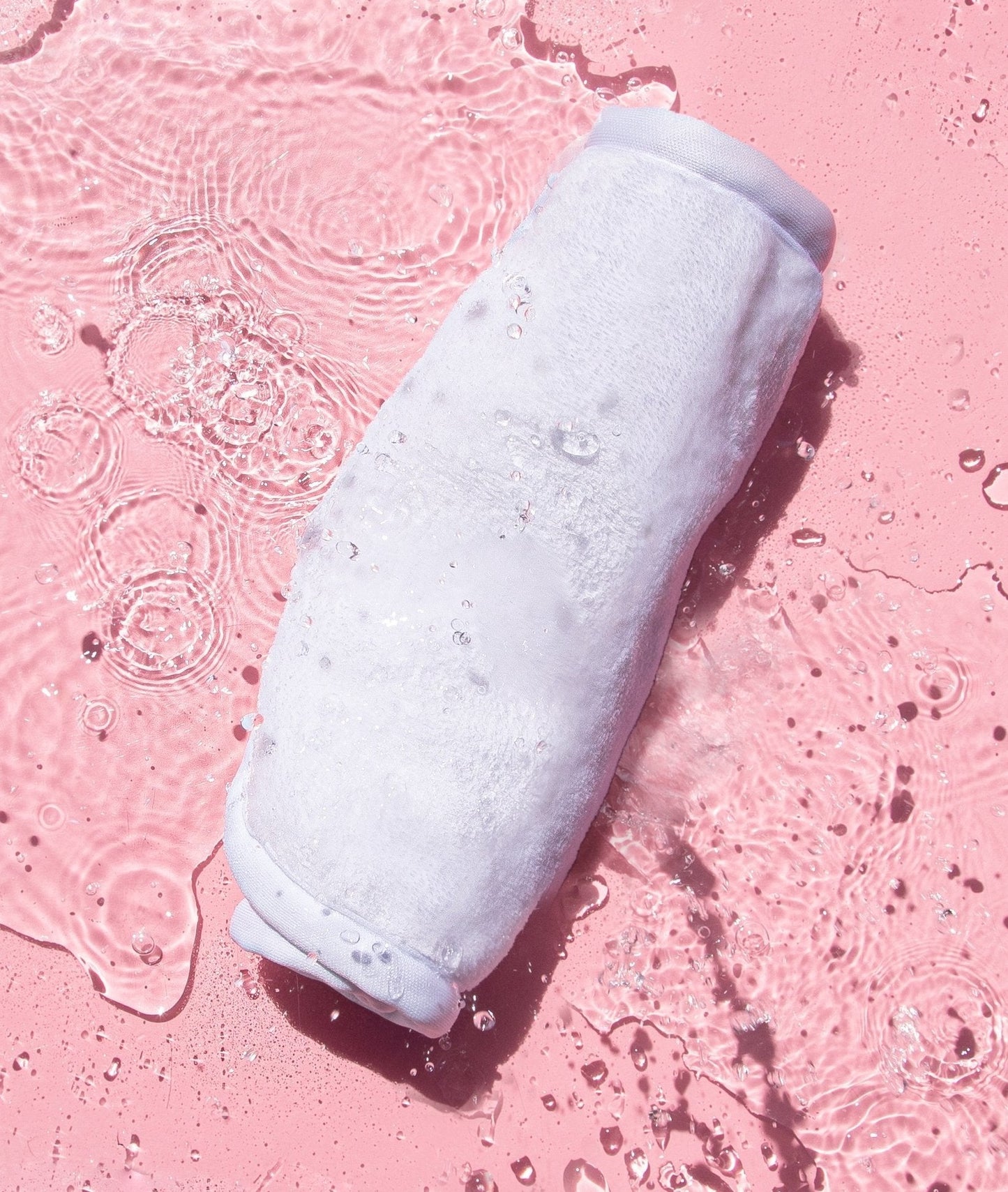 Rolled up Clean White MakeUp Eraser surrounded by water.