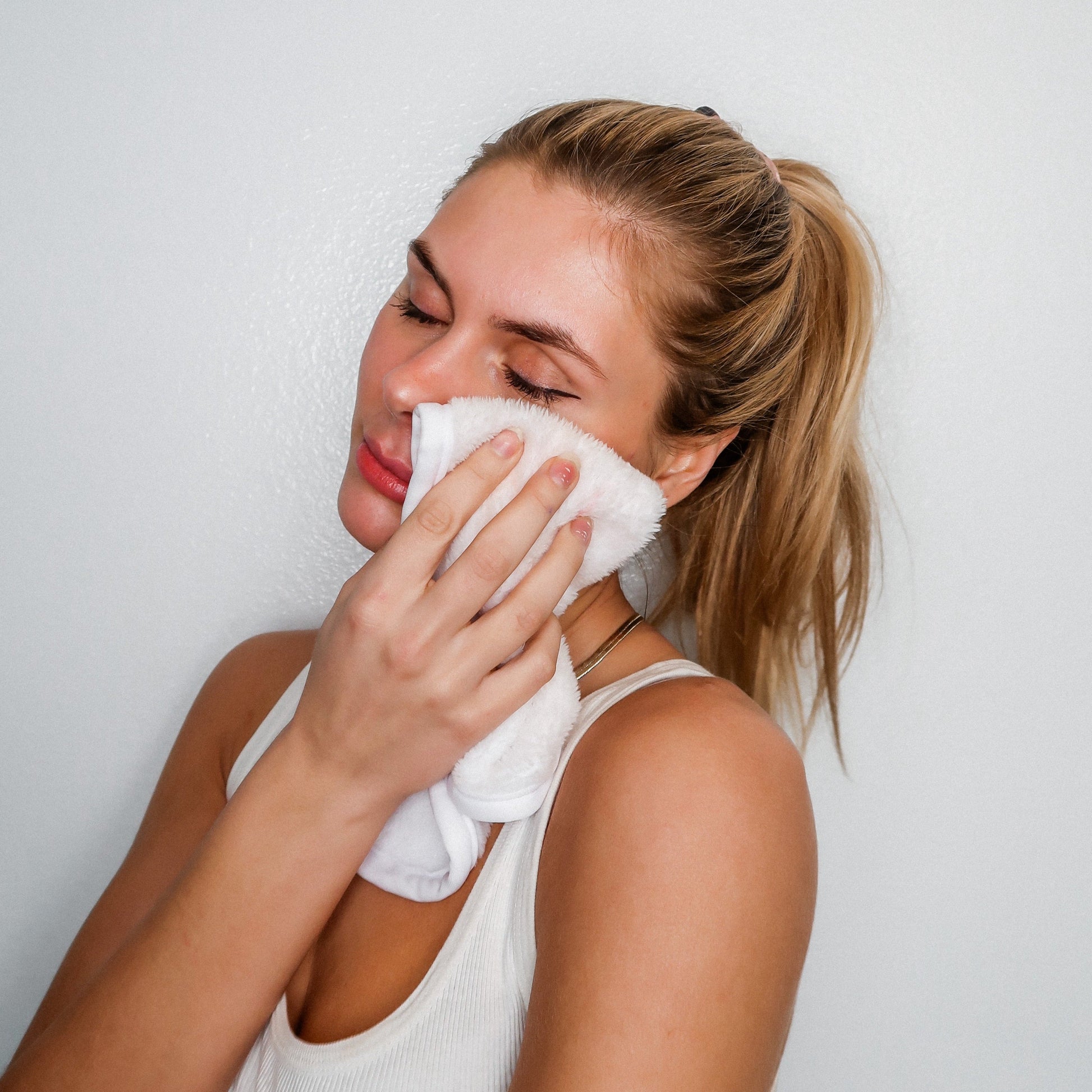 Woman smiling and holding Clean White MakeUp Eraser up to her face.