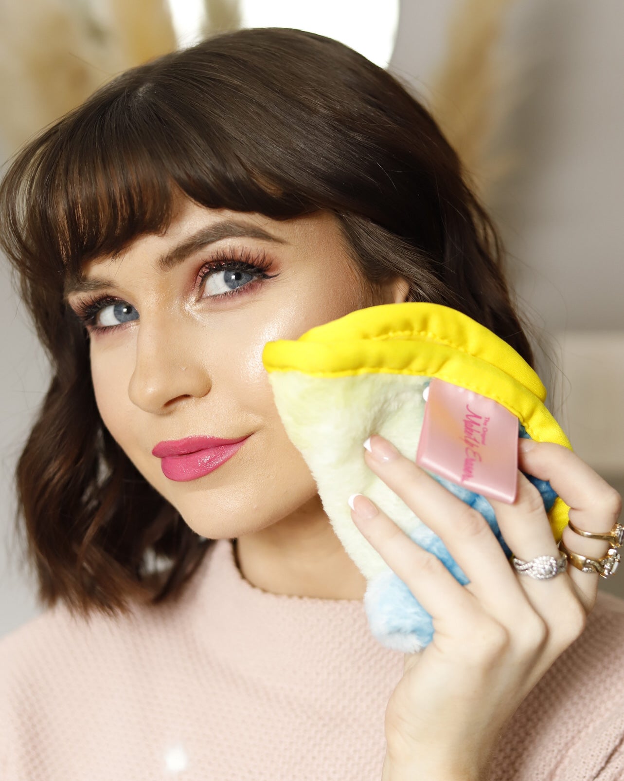 Woman smirking and holding charity: water MakeUp Eraser up to her face.